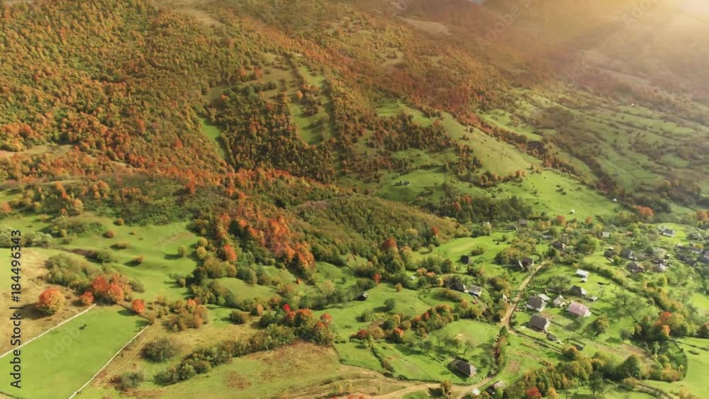 Aerial View Drone Flight over beautiful village located in canyon along the mountain river. Green hills, orange tree forests in sunset soft light. Carpathians, Ukraine, Europe. 4K. Camera turns right Aerial View Drone Flight over beautiful village located in canyon along the mountain river. Green hills, orange tree forests in sunset soft light. Carpathians, Ukraine, Europe. 4K. Camera turns right