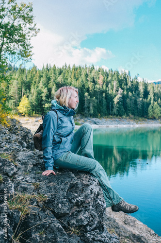 Девушка путешественник сидит на скале над озером в Черногории