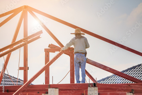 welder workers installing steel frame structure of the house roof at building construction site © Kwangmoozaa