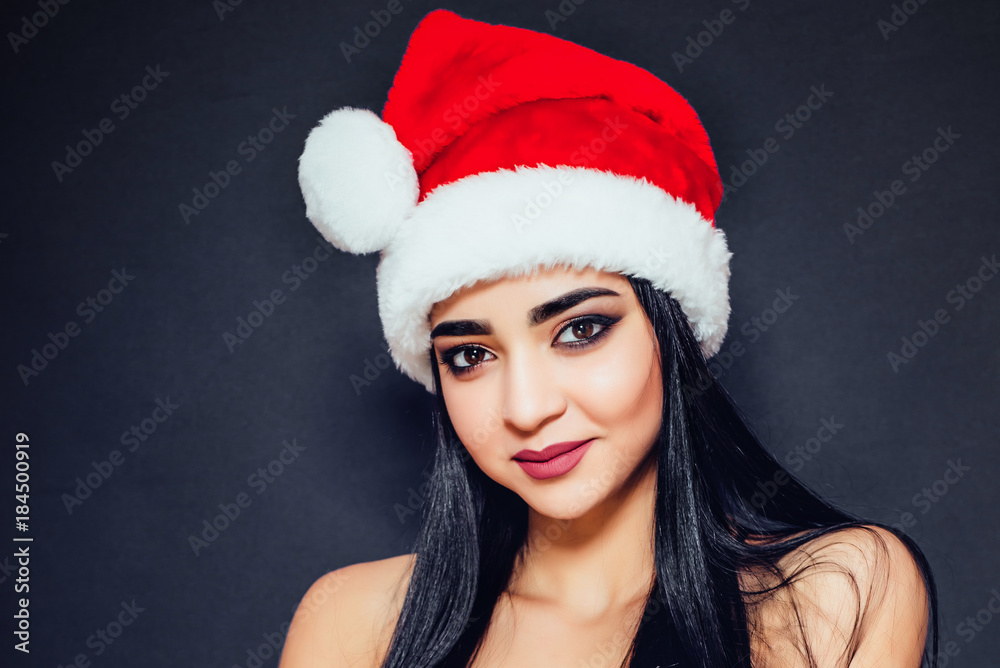 Beautiful woman with black straight hair and a Santa Claus hat on a dark background smiling. Close-up. Space for text
Beautiful woman with black straight hair and a Santa Claus hat on a dark background smiling. Close-up. Space for text
