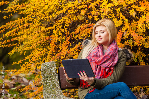 Woman relaxing sitting on bench in park using tablet