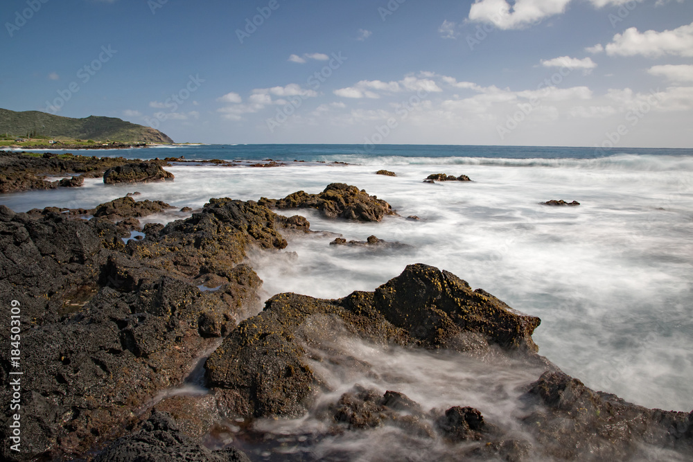 Ocean waves flowing into rocks and back to the sea creating beautiful water pattern, Sandy beach, Oahu, Hawaii