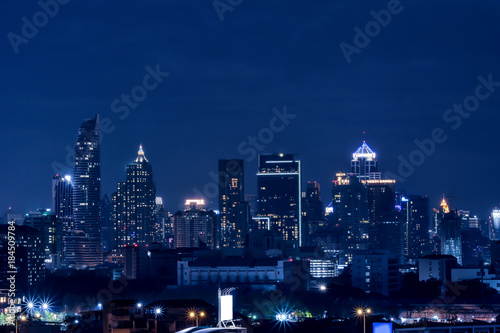 Silhouettes of skyscrapers in the dark town and blue background. © Rattana