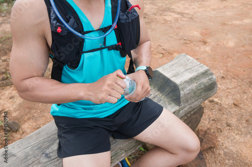 Athletic runner opening the water in the foresr trauk photo