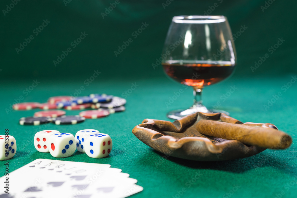 Cards, dice, chips, a glass of cognac and cigar on a green baize, the game is. Cards, dice, chips, a glass of cognac and cigar on a green baize, the game is.