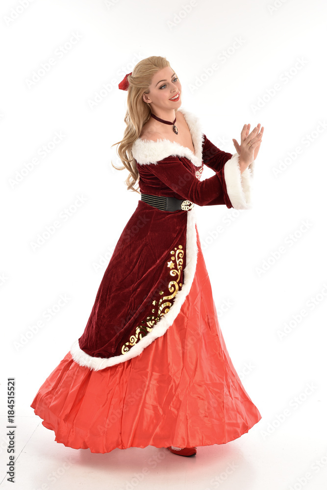 full length portrait of pretty blonde lady wearing red and white christmas inspired costume gown, standing pose on white background.