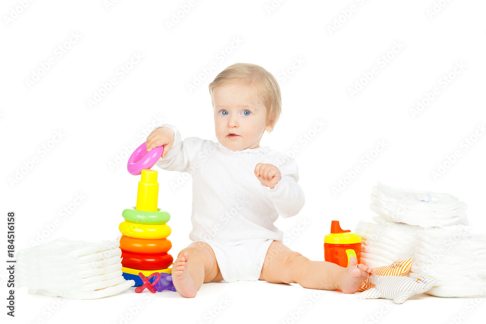 Caucasian kid with stacked diapers and toys isolated on white background Caucasian kid with stacked diapers and toys isolated on white background