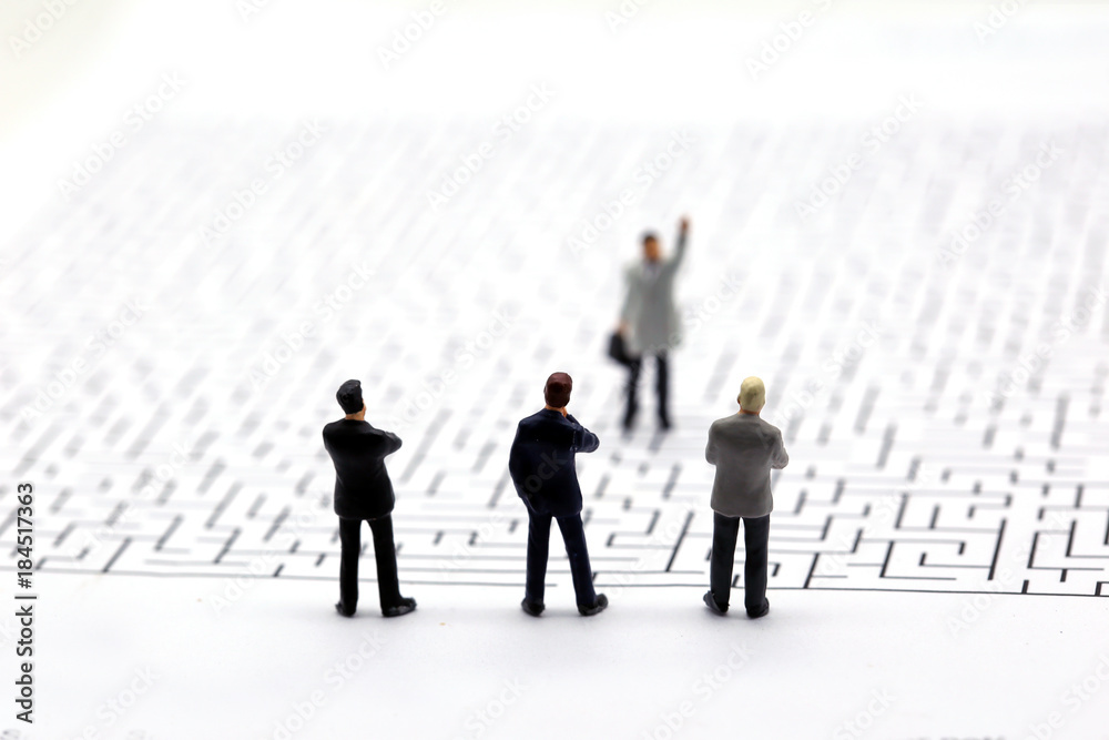 Miniature people: Businessman teams standing on center of maze Miniature people: Businessman teams standing on center of maze