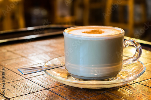 coffee cup with milk froth on wooden chess table