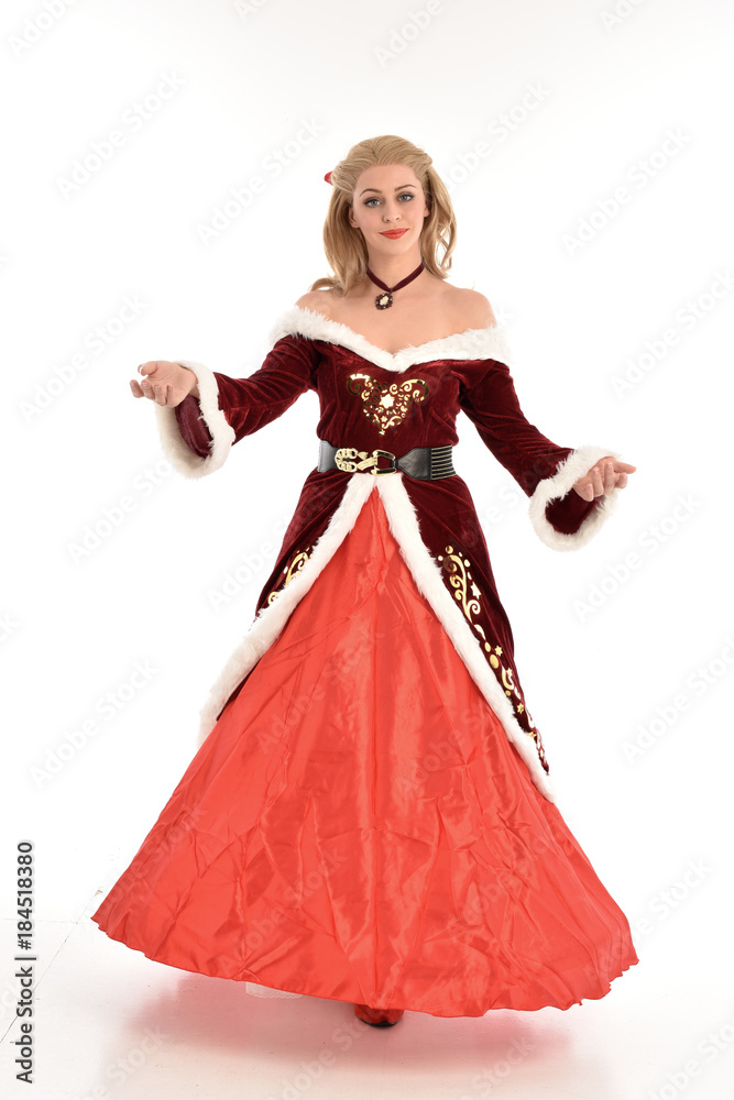 full length portrait of pretty blonde lady wearing red and white christmas inspired costume gown, standing pose on white background.