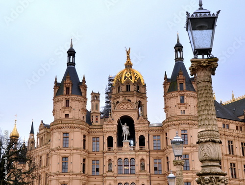 Schweriner Schloss mit goldener Kuppel und zwei Türmen sowie antiker Laterne im Vordergrund photo