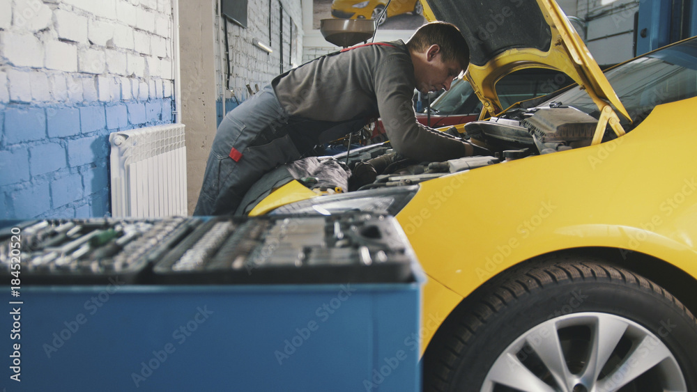 Mechanic in car service - repairing in engine compartment Mechanic in car service - repairing in engine compartment