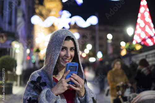 Woman sending voice message in winter city image with city lights in background