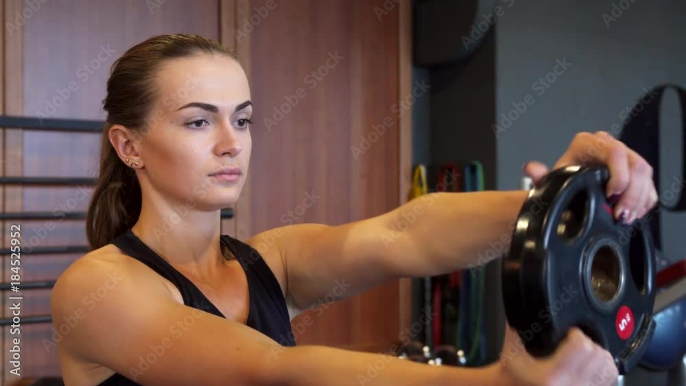 The young girl is doing exercises in the gym using a special round dumbbell The young girl is doing exercises in the gym using a special round dumbbell