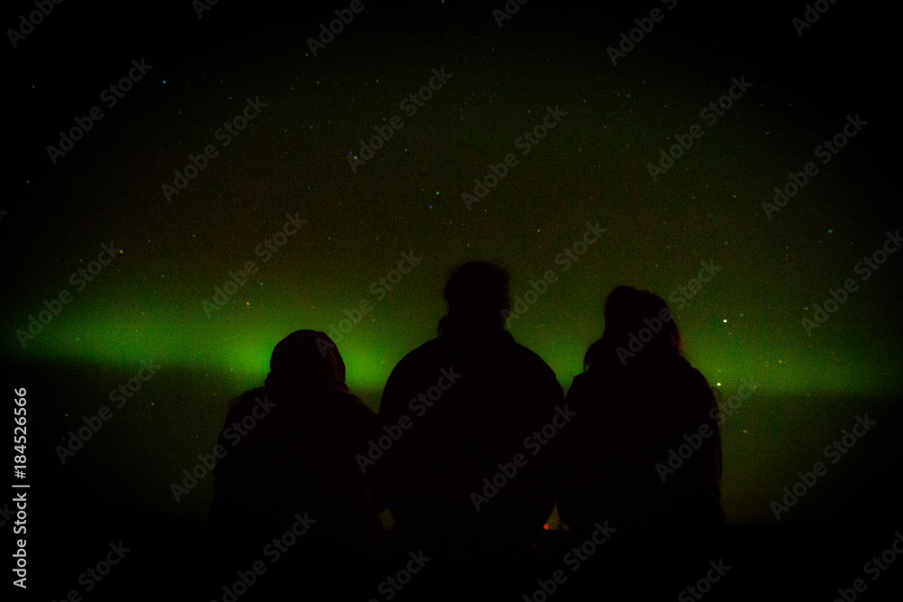 northern lights arcoss the blacked skies of an Alaskan life staring up at the stars.  Northern lights across the black spruces on the Alaskan Range, Silhouettes cast across the sky and clouds cascaded