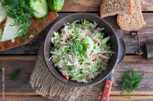 prepared salad with cabbage and ham on a wooden table, top view, horizontal