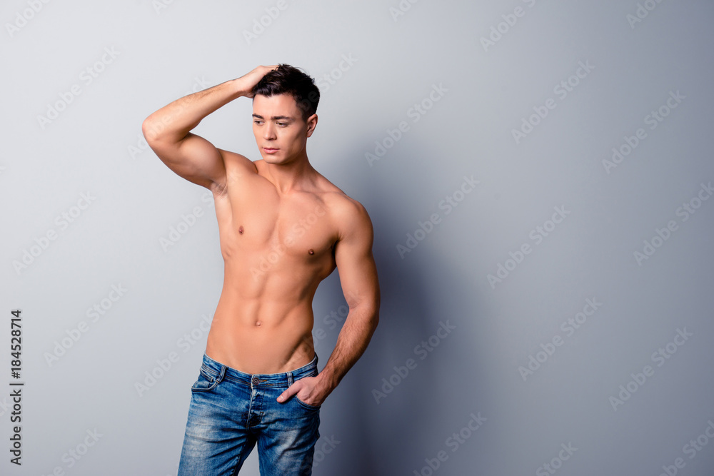 Sexy handsome virile confident  srtong muscular man is combing his hair, he is isolated on grey background, copyspace