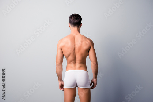 Cuadro en lienzo Back view photo of handsome confident guy with strong back and shoulders, wearin