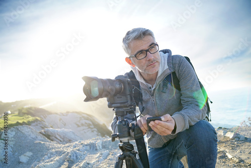 Photographer using wifi device to look at photo shots photo