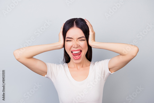 Closeup portrait of  bitter displeased, upset, angry woman screaming with open mouth  and holding her head with hands © deagreez
