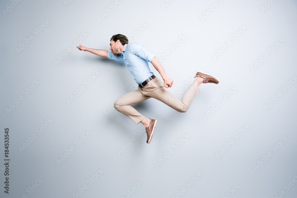 Happy, attractive, handsome, young, cool, joyful man with bristle jumping in air showing superman pose over grey background Happy, attractive, handsome, young, cool, joyful man with bristle jumping in air showing superman pose over grey background