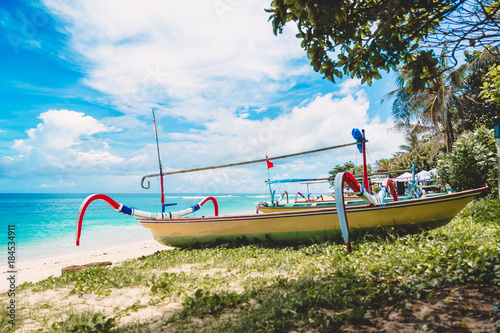 Tropical island in Indonesia, blue ocean and traditional boats on a sandy beach