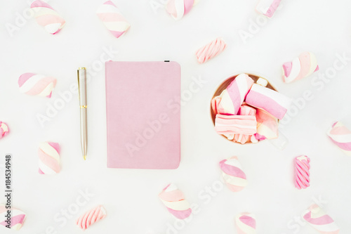 Beauty concept of marshmallow with cappuccino mug and notebook on white background. Flat lay, top view