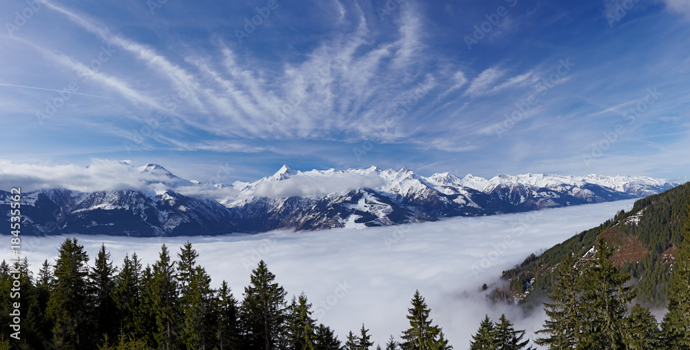 Panoramic view to foggy valley and Alps Mountains with blue sky and white fleecy clouds in background at Zell Am See Austrian Schmitten ski resort in march month