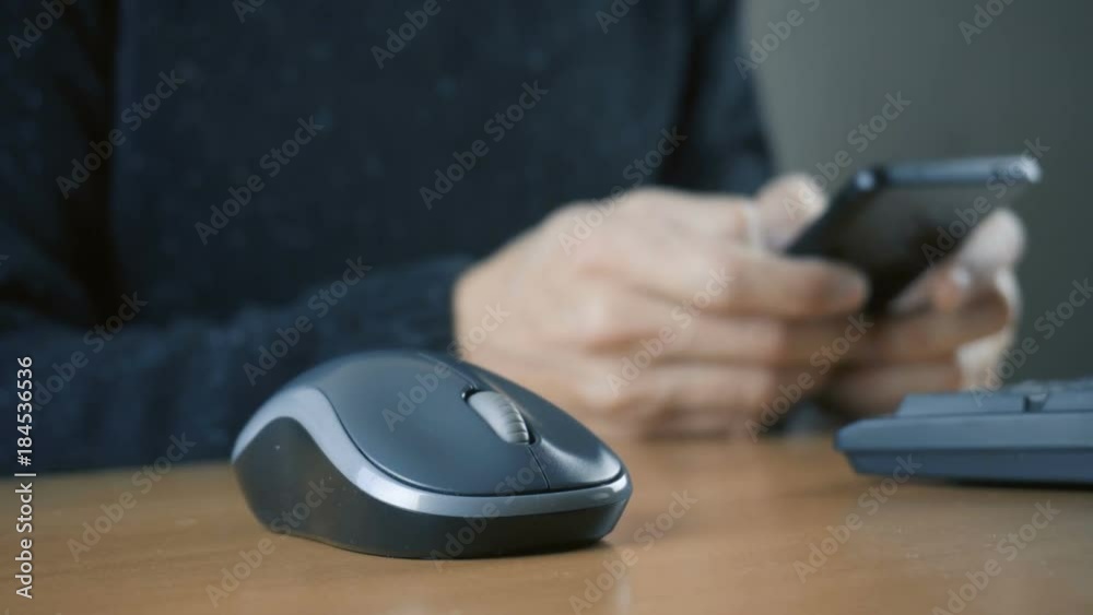 Hand of a man working at computer and using smartphone Hand of a man working at computer and using smartphone