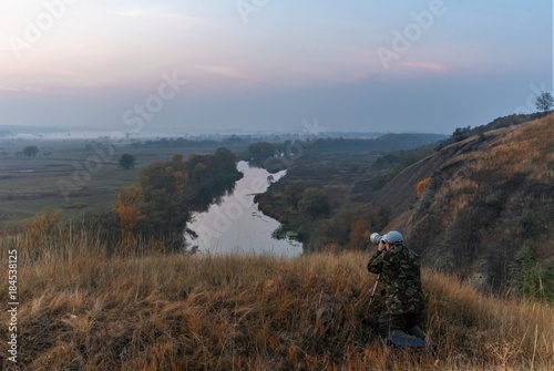 the photographer is shooting the autumn landscape with the sunrise by the river