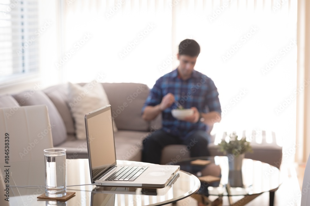 Man having breakfast with laptop and glass of water on table Man having breakfast with laptop and glass of water on table