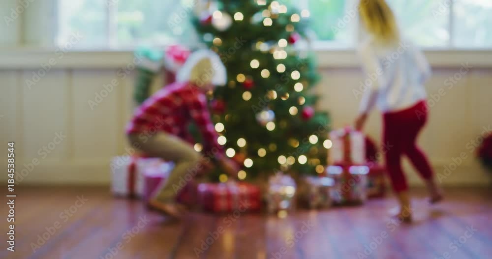 Happy young kids running to Christmas tree to open presents on Christmas morning