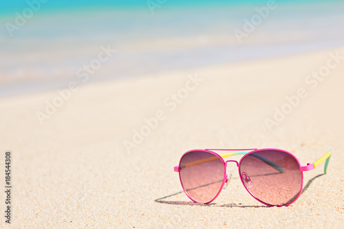 Pink sunglasses on sandy tropical beach in summer