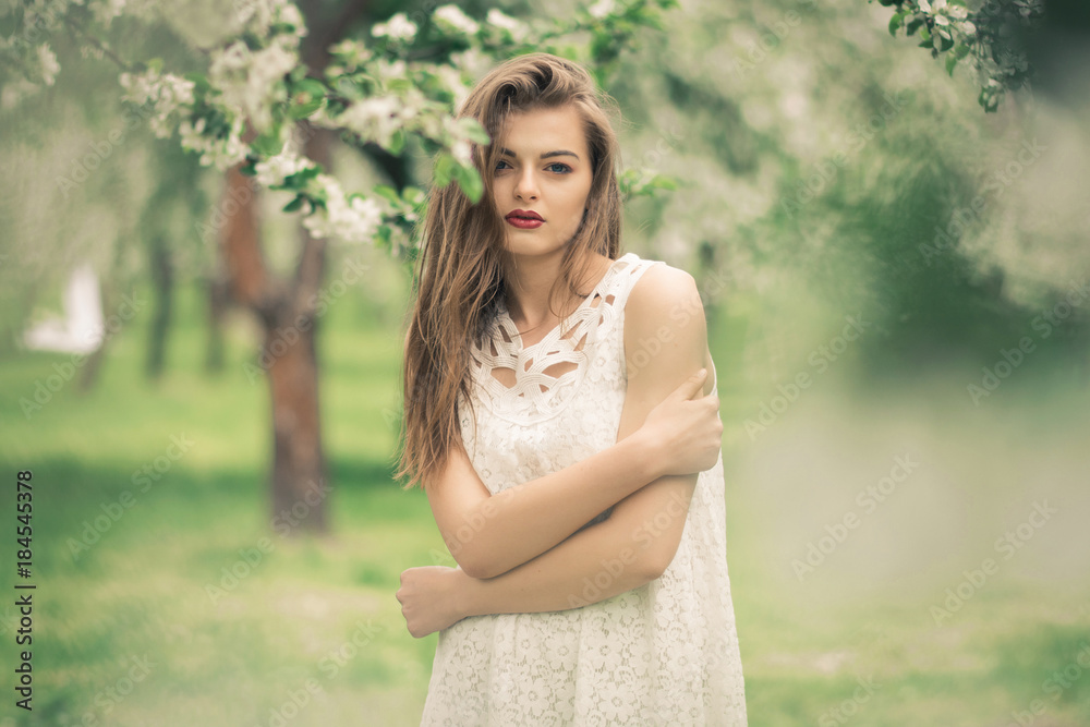 Beautiful woman enjoying sunny spring day in park during cherry blossom season Beautiful woman enjoying sunny spring day in park during cherry blossom season