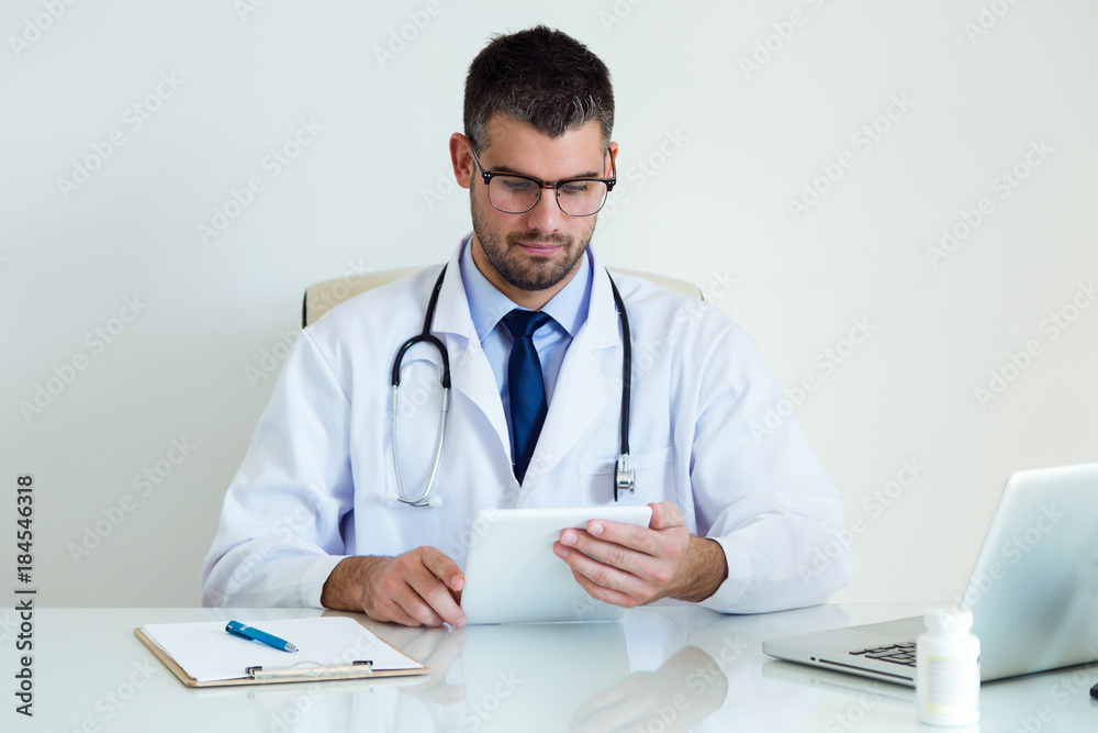 Confident male doctor using his digital tablet in the office. Confident male doctor using his digital tablet in the office.