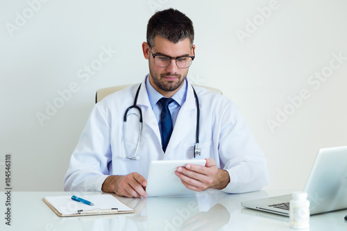 Confident male doctor using his digital tablet in the office.