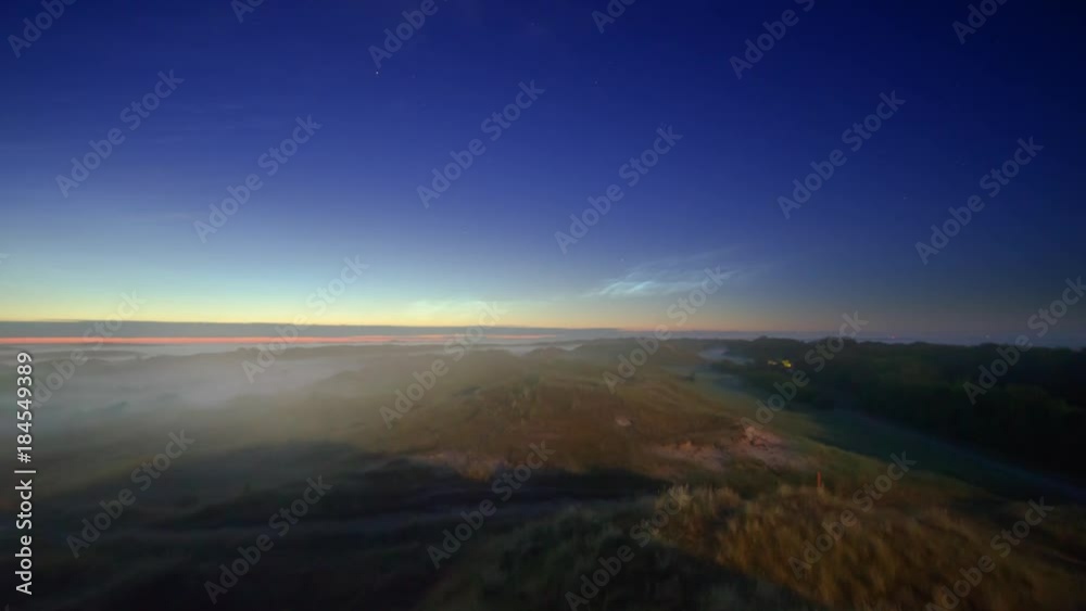 noctilucent clouds NLC with early morning fog over landscape island North Sea in summer twilight timelapse noctilucent clouds NLC with early morning fog over landscape island North Sea in summer twilight timelapse