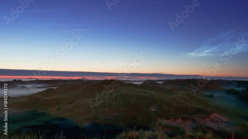 noctilucent clouds NLC with early morning fog over landscape island North Sea in summer twilight timelapse photo