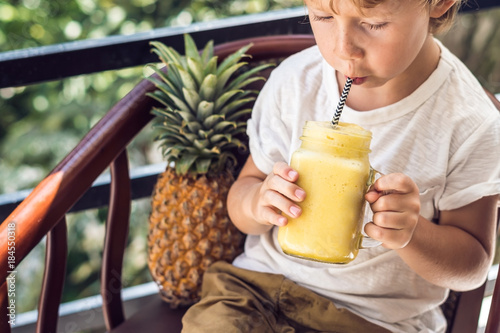 A boy drinks a pineapple smoothie on the terrace photo