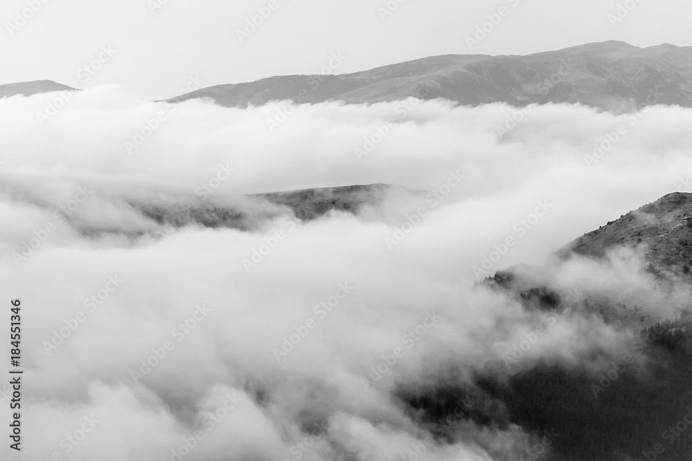 A tranquil mountain scene with clouds cover on a hill. Black and white