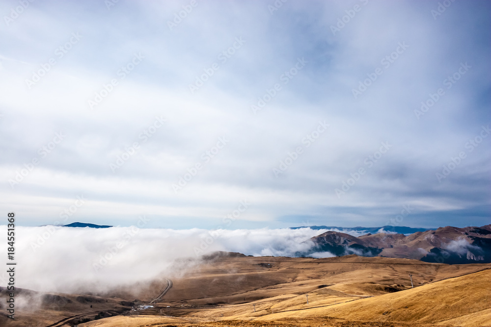 A tranquil mountain scene with clouds cover on a hill. Some cabins in the backgroud A tranquil mountain scene with clouds cover on a hill. Some cabins in the backgroud