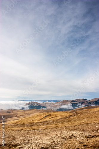 A tranquil mountain scene with clouds cover on a hill. Red guiding signs for snow