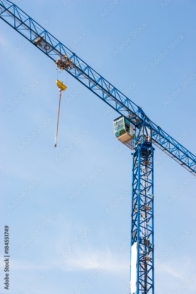 Industrial construction crane hoisting against blue sky Industrial construction crane hoisting against blue sky