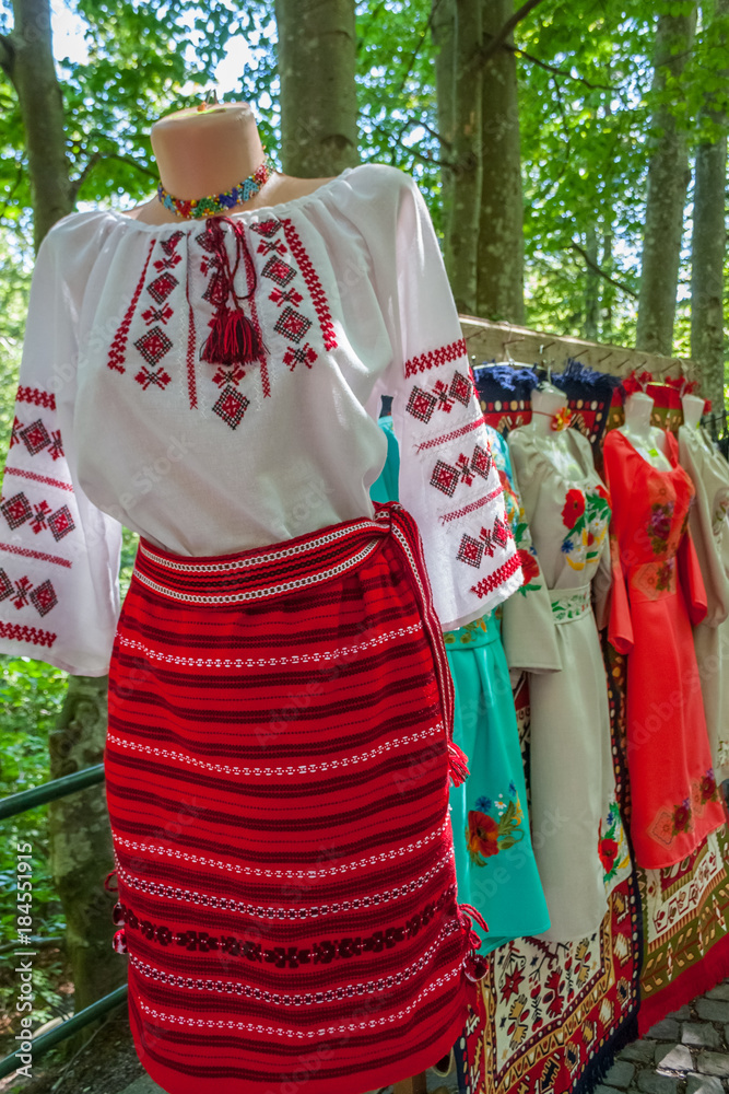 Romanian traditional costumes on mannequins and hangers shown outdoors