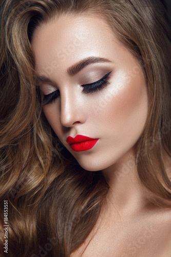 Beautiful woman portrait with red lips, curly hair on black background.