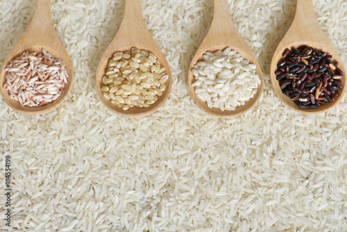 Top view different rice on wooden scoop with jasmine rice background, Various rice organic on wooden spoon collection