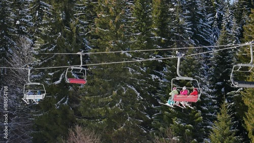 Colorful ski lift chairs in ski resort on winter day. 30 sec. 30 fps Static Close up 4K shot. Couple of skiers shake their hands happily. People ride skilift chairs up the mountain in Pamporovo winter photo