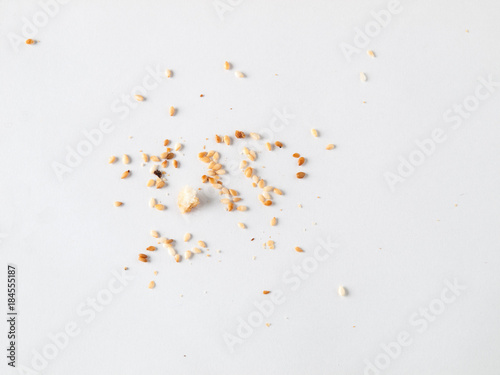 Scattered sesame seeds and crumbs isolated on white background photo