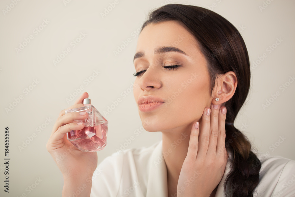 young beautiful woman holding a spray bottle of perfume and smelling aroma young beautiful woman holding a spray bottle of perfume and smelling aroma