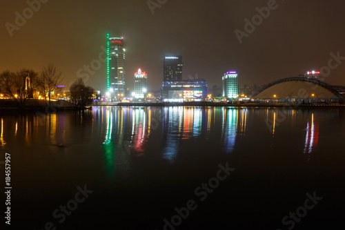 lights of the night city. Light skyscraper reflected in the lake water with fog